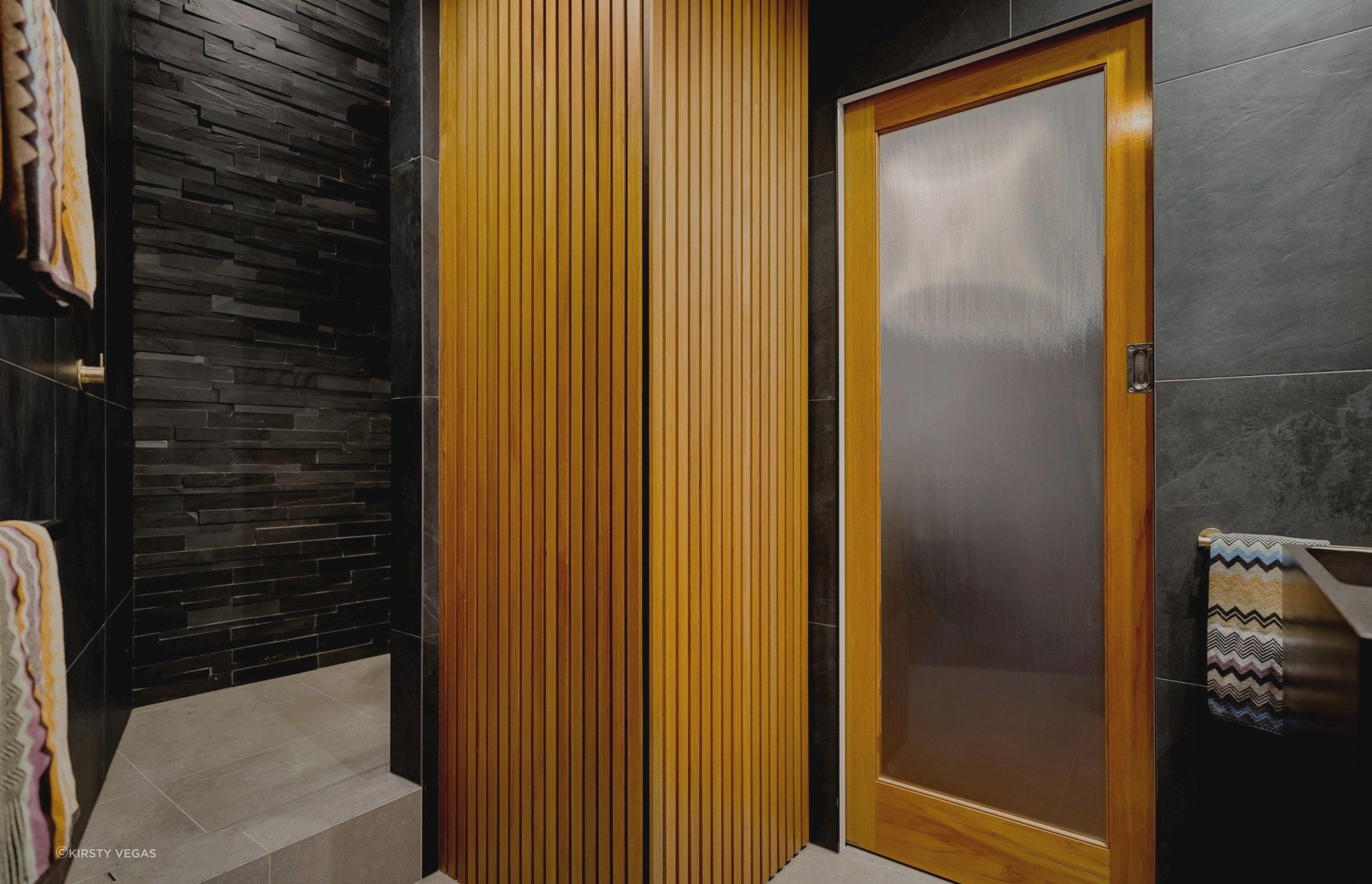 The warm-toned Rimu wood paneling elegantly conceals a hidden laundry cupboard, while a custom sliding door has been crafted to complement the heritage character of the building and coordinate seamlessly with the other apartment doors.