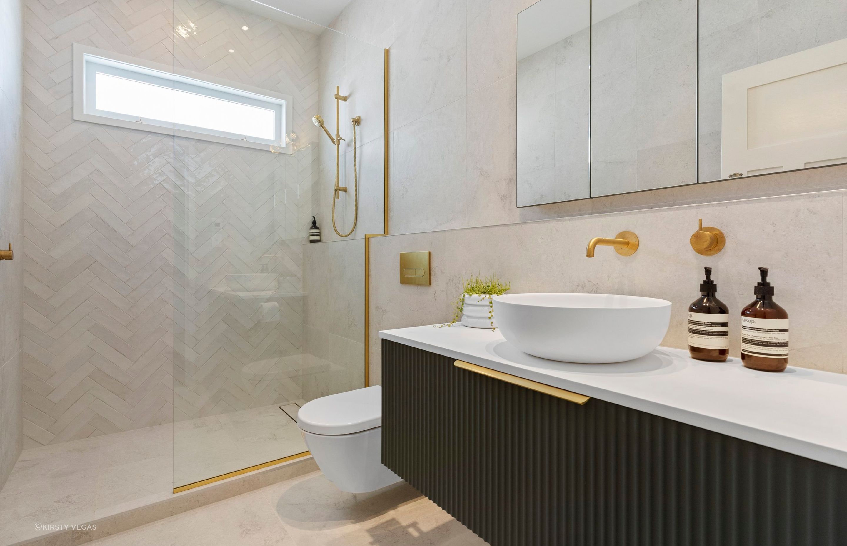 This serene monochromatic palette provides the perfect backdrop for the stunning ‘Kombu’ green fluted wall-hung vanity, allowing it to truly come alive within the space. The rich, textured green hue adds a vibrant pop of color while maintaining a contemporary yet timeless quality that elevates the overall design of the bathroom. This clever juxtaposition underscores the vanity as a striking focal point, infusing the room with character and charm while enhancing its tranquil atmosphere.