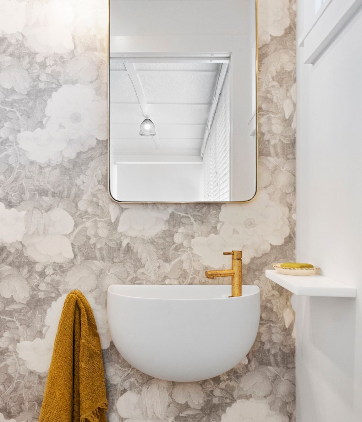 The stunning curved wall-hung Lavamani round basin harmoniously complements the custom linen wallpaper, creating a seamless blend of elegance and artistry. Its graceful shape adds visual interest and softens the overall aesthetic, while the intricate floral patterns of the wallpaper enhance the basin's refined design. Together, they create a beautifully curated focal point in the powder room, infusing the space with a sense of style and tranquility.