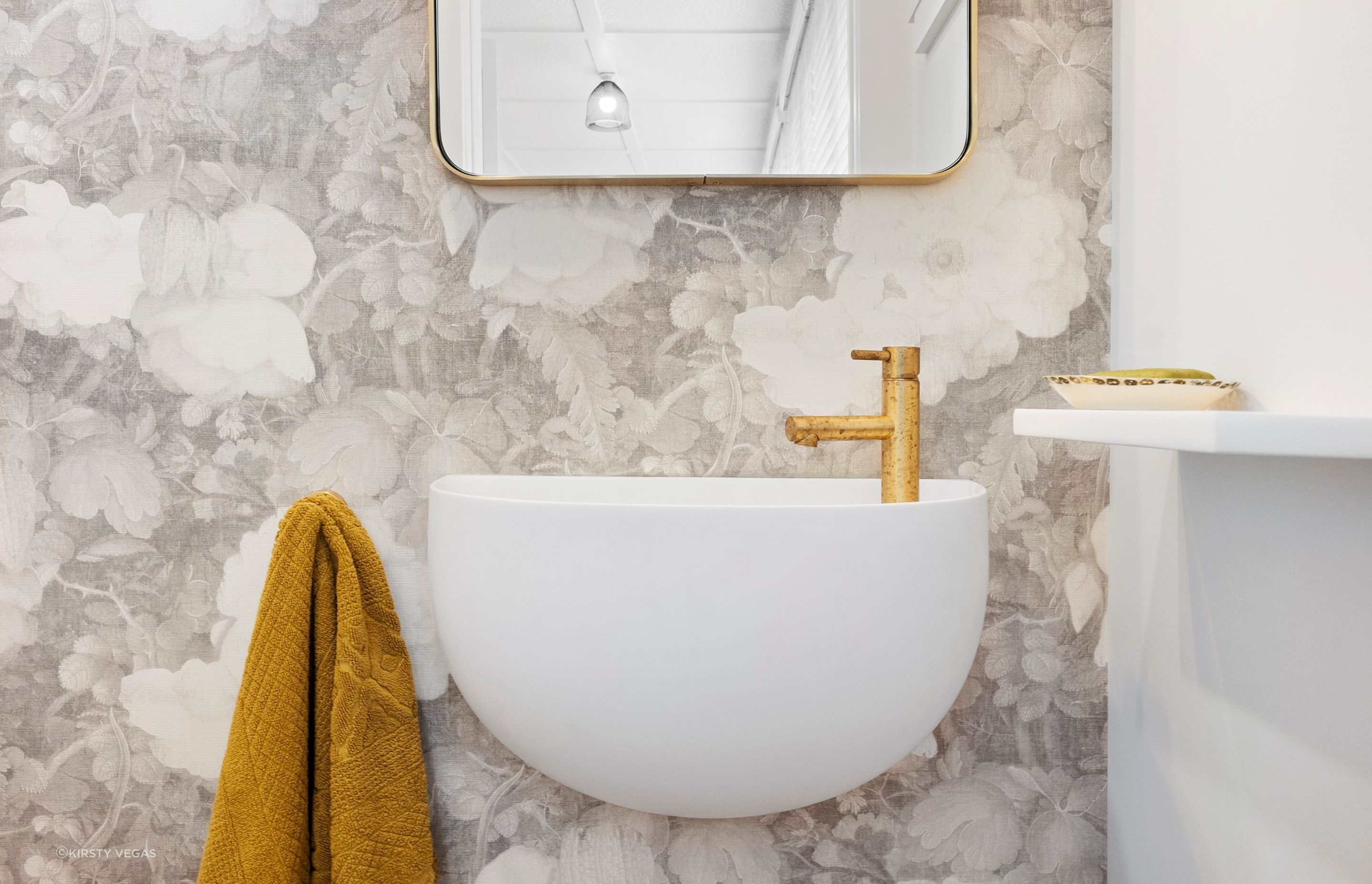 This charming powder room is a delightful blend of elegance and natural beauty, accentuated by the organic brushed brass Progetto tapware that adds a touch of sophistication. The stunning wall-hung Lavamani round basin perfectly complements the space, harmonizing beautifully with the custom linen floral wallpaper. This combination creates a serene and inviting atmosphere, making the powder room not just functional, but also a stylish retreat that reflects refined taste and attention to detail.