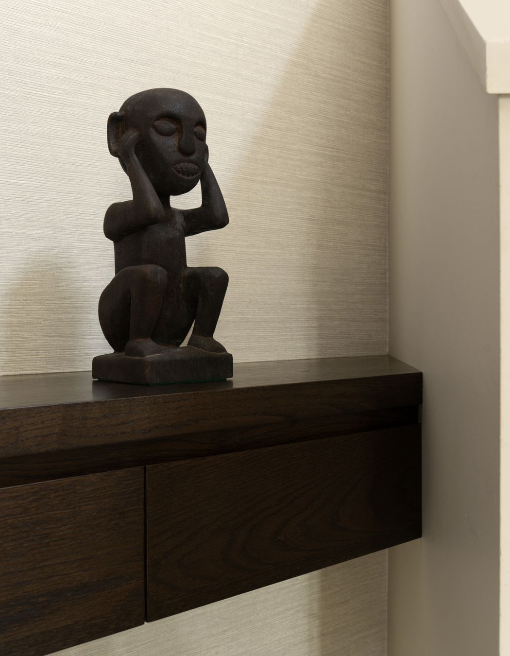 Oak floating drawers with grasscloth wall covering.