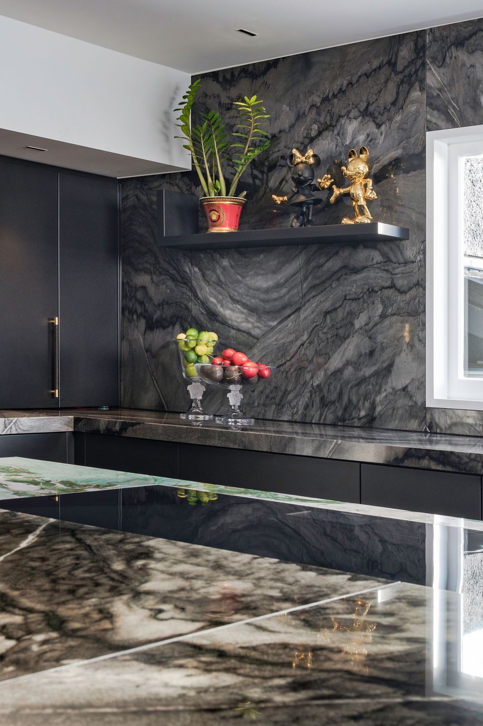 A simple L-shaped shelf is a refined design evolved from Versace’s signature border motif. This quietly interrupts the textured stone-clad wall to provide opportunity to display playful sculptures, just for fun.