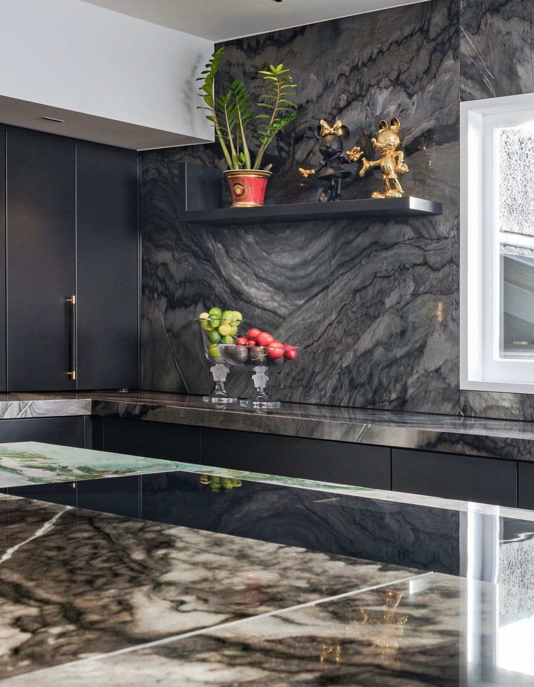 A simple L-shaped shelf is a refined design evolved from Versace’s signature border motif. This quietly interrupts the textured stone-clad wall to provide opportunity to display playful sculptures, just for fun.