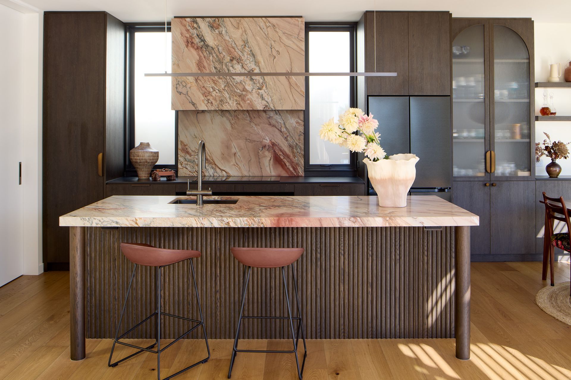 The bespoke kitchen combines richly detailed oak joinery with dramatic granite surfaces to create a timeless family hub at the centre of the home.