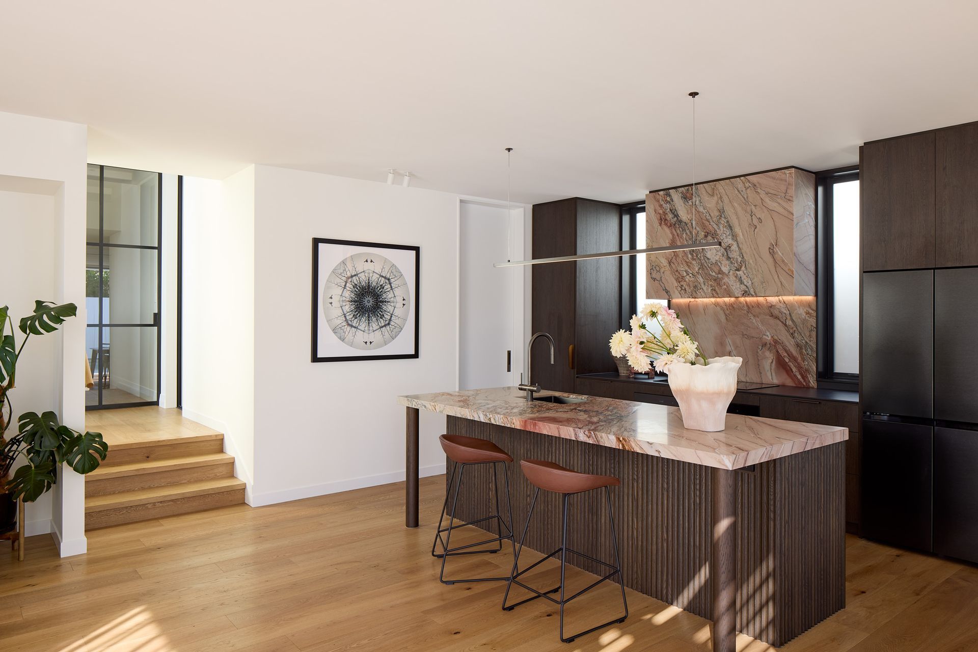 The open-plan kitchen connects seamlessly to the rest of the home through elegant steel cavity sliders. Carefully crafted joinery and a restrained material palette create a calm, contemporary interior within the renovated bungalow.