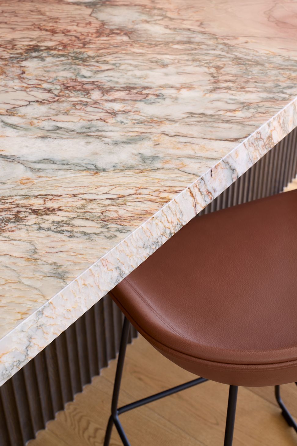 A close-up of the kitchen island highlights the beautifully veined granite benchtop, stained oak cabinetry and Hay bar stools, showcasing the craftsmanship and materiality that define the home.