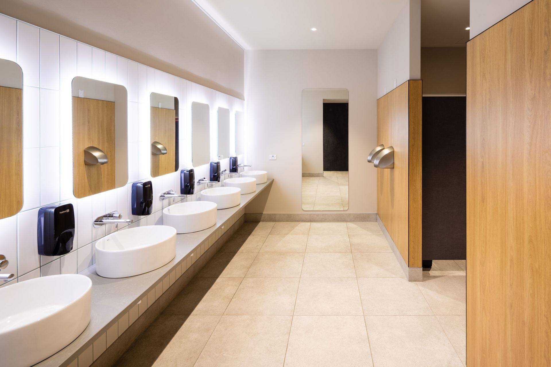 A sleek, modern aesthetic features in the bathrooms with LED back-lit mirrors and and ceramic wall and floor tiles. Photography by Clinton Lloyd.