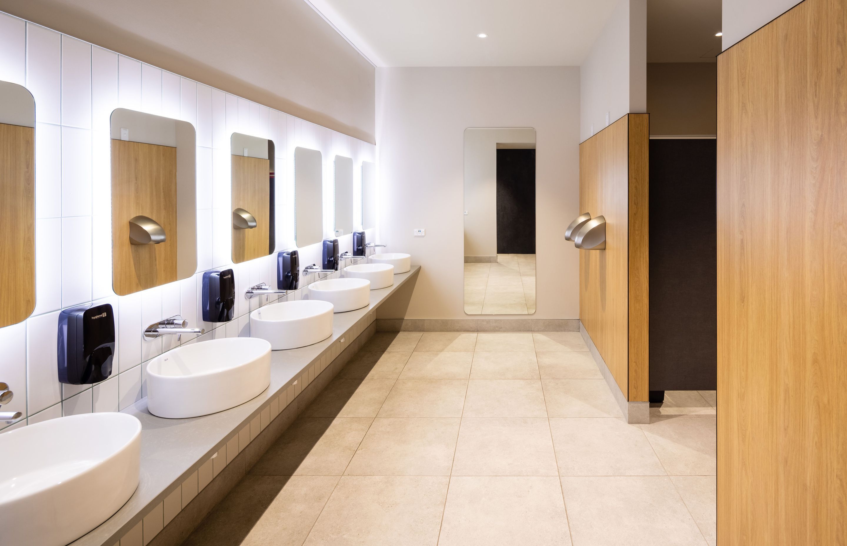 A sleek, modern aesthetic features in the bathrooms with LED back-lit mirrors and and ceramic wall and floor tiles. Photography by Clinton Lloyd.