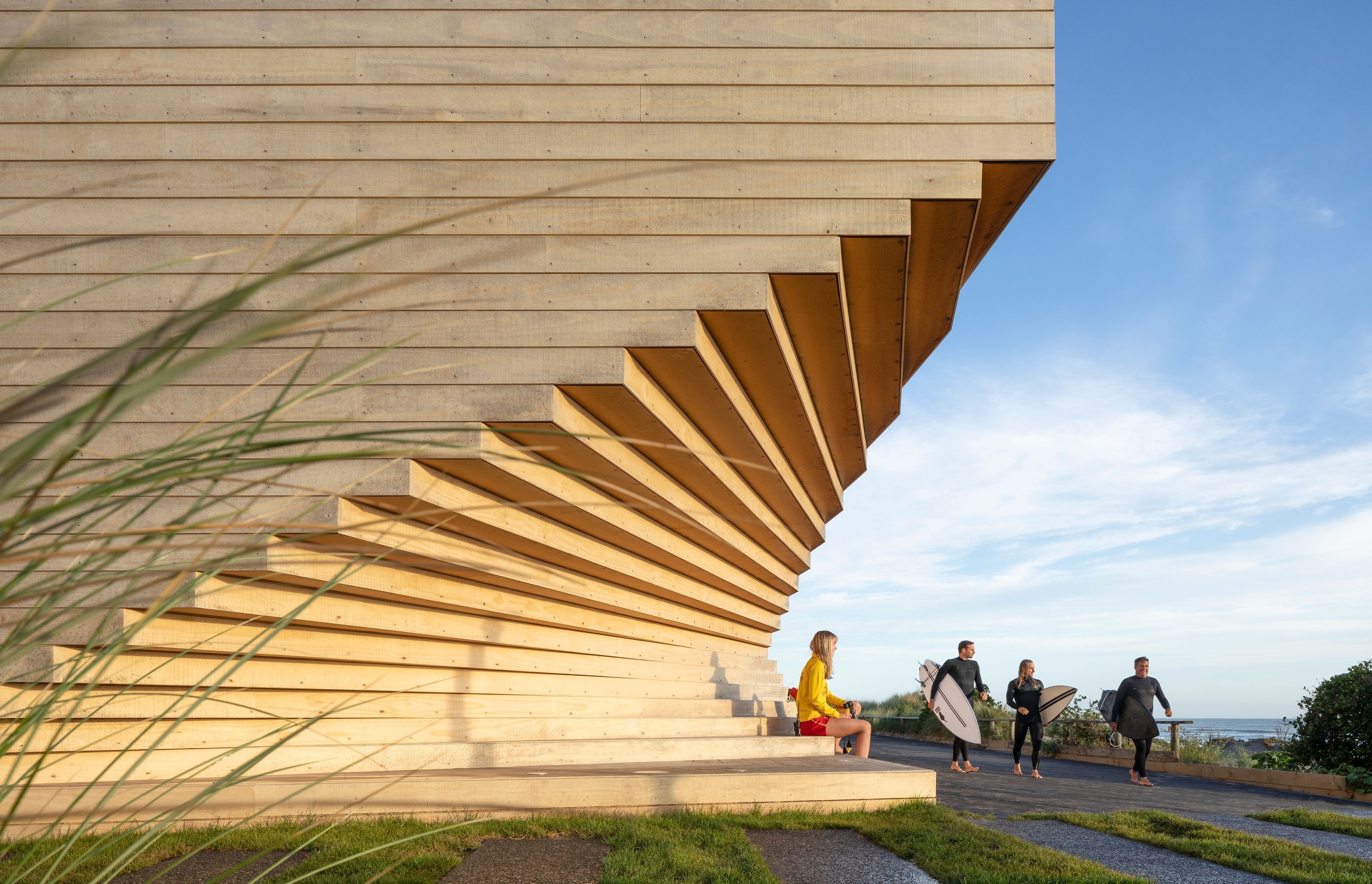 Fanning towards the ocean, the building's architectural form mimics the curves and undulations in the surrounding sand and driftwood.