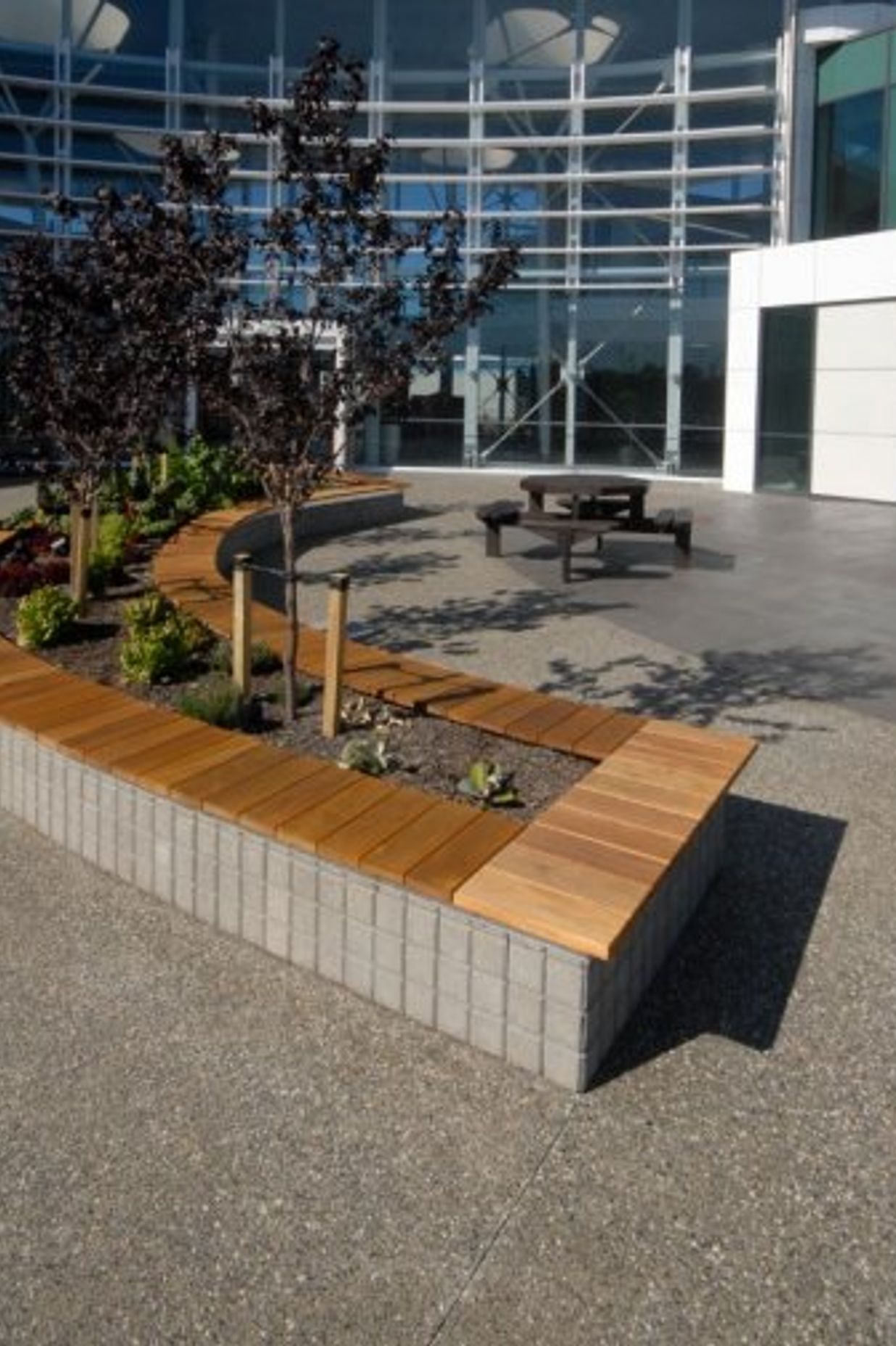 Exposed aggregate Otautahi with 10% white stone and Holland Set pavers honed in Charcoallaid vertically as the base for the planter box and seating