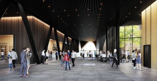 A large contemporary public interior or commercial lobby with a dramatic black slatted ceiling, dark timber or wood-look wall panels, substantial angled black structural columns, expansive glazing, and a broad grey tiled floor. Numerous people move through the open hall, with café-style seating and retail or display areas along the sides. Warm integrated lighting contrasts with the dark architectural finishes, while a bright arched opening anchors the far end.