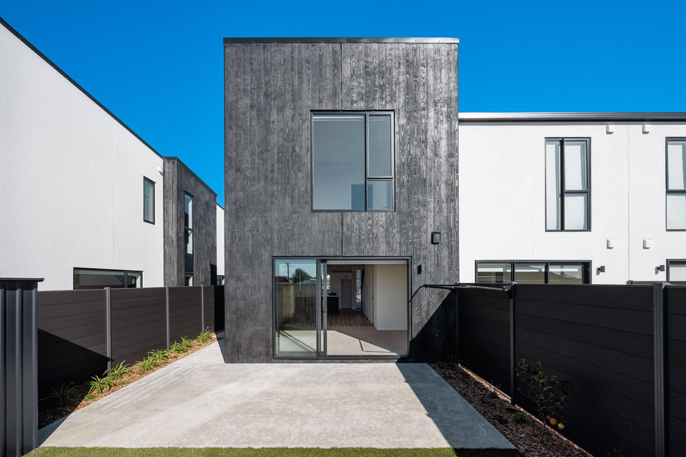 Dark tinted timber board-formed precast concrete contrasting with the smooth white panels