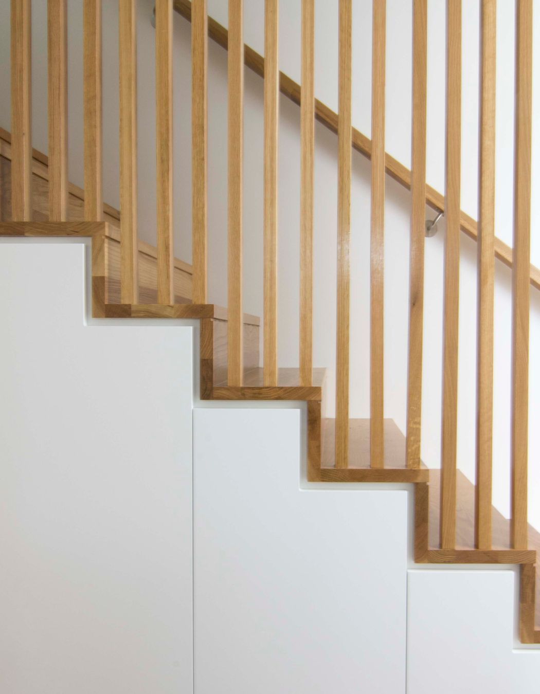 A seamless detail to the staircase and balustrade junction. Concealed storage below stairs to maximise use of space.