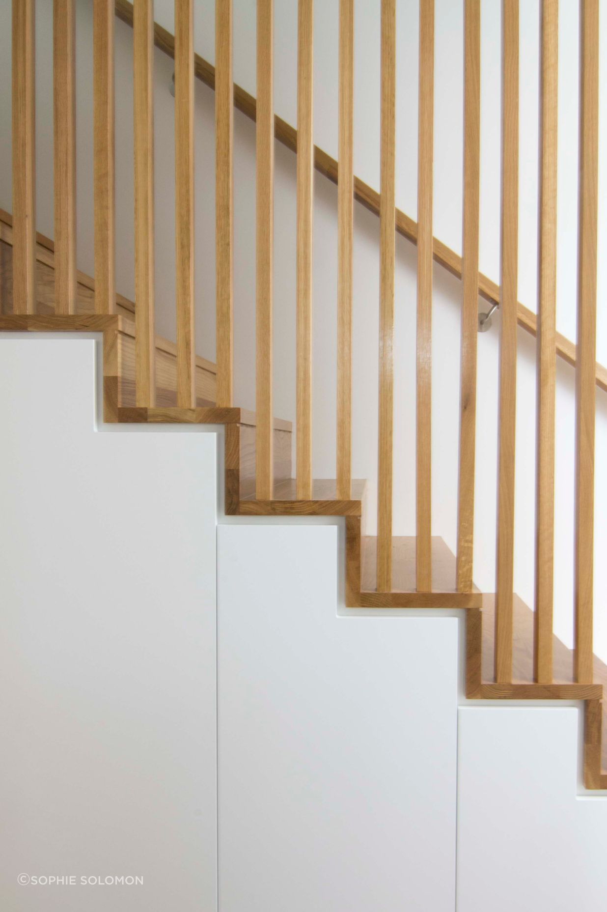 A seamless detail to the staircase and balustrade junction. Concealed storage below stairs to maximise use of space.