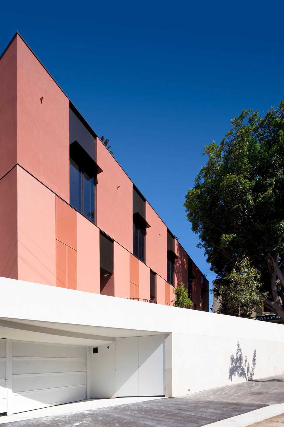 Textural red upper volume atop a light sandstone base