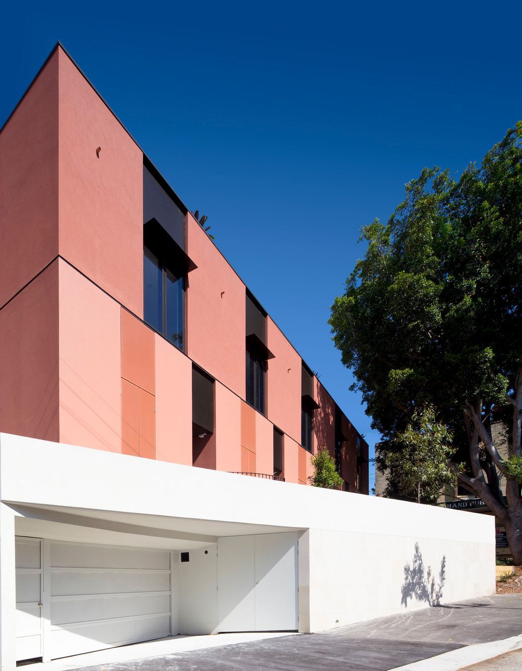 Textural red upper volume atop a light sandstone base