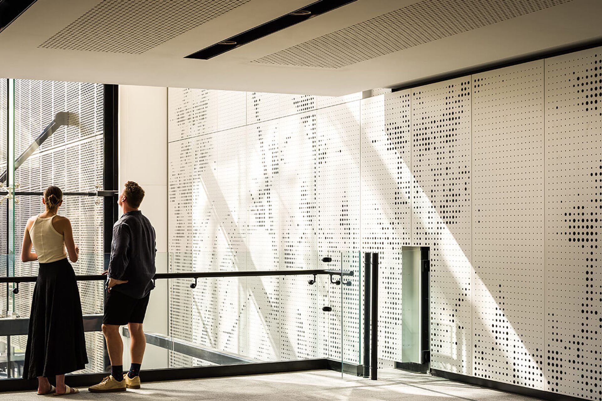 Perforated screens on the interior of the atrium complement the perforated metal screens that conceal the car parking building.
