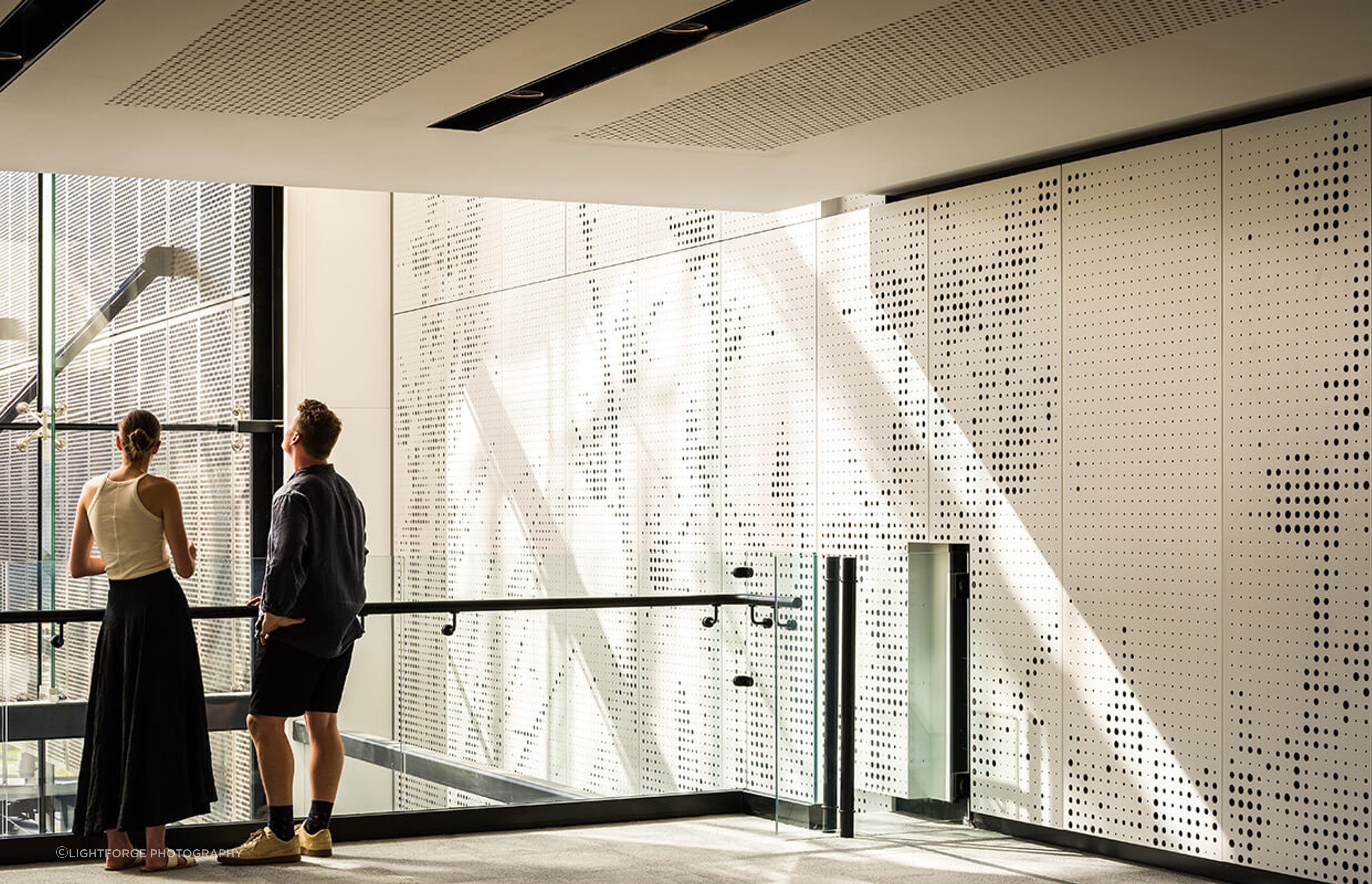 Perforated screens on the interior of the atrium complement the perforated metal screens that conceal the car parking building.