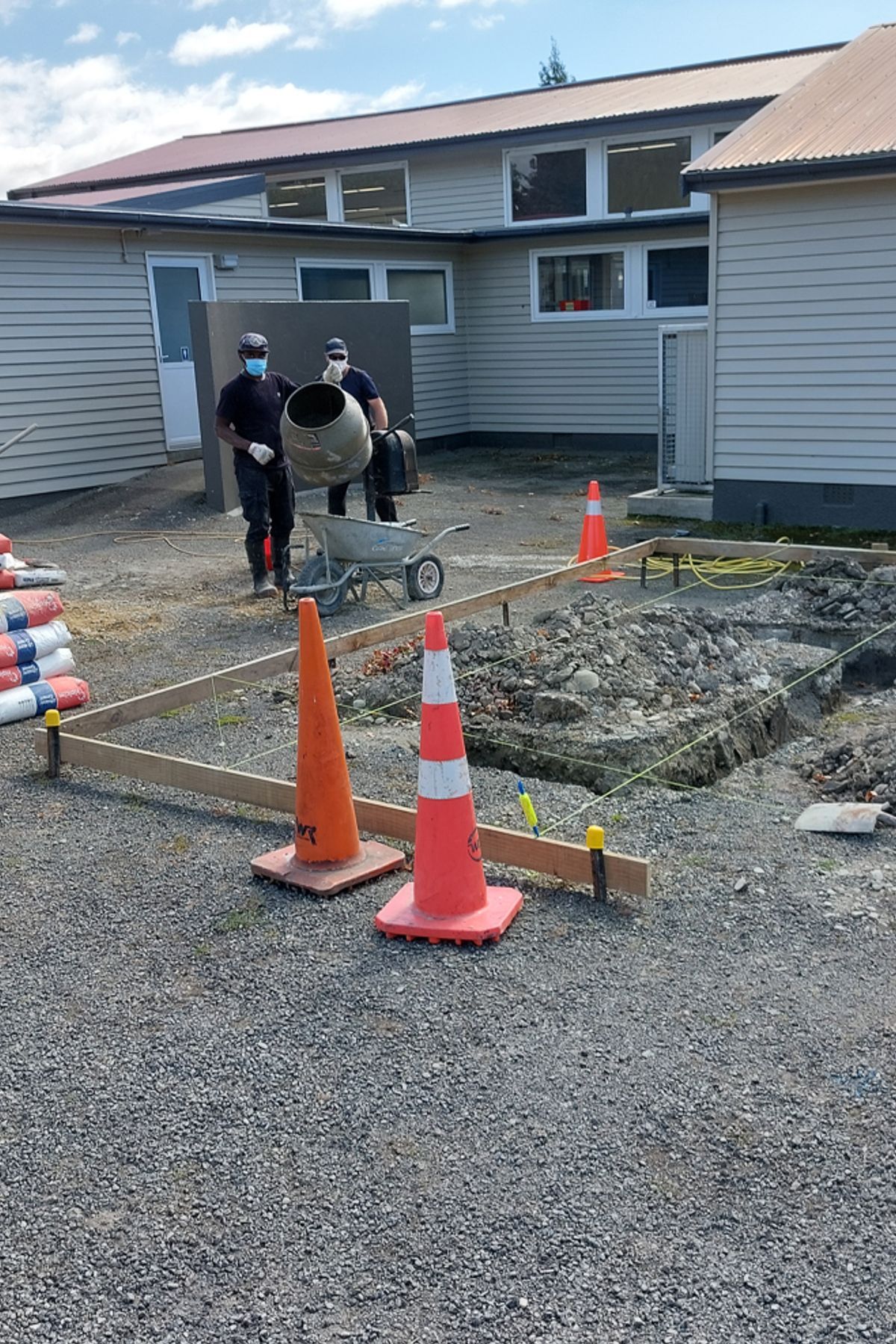 Two of our team mixing up concrete for the foundation whilst another floats the concrete on the other side