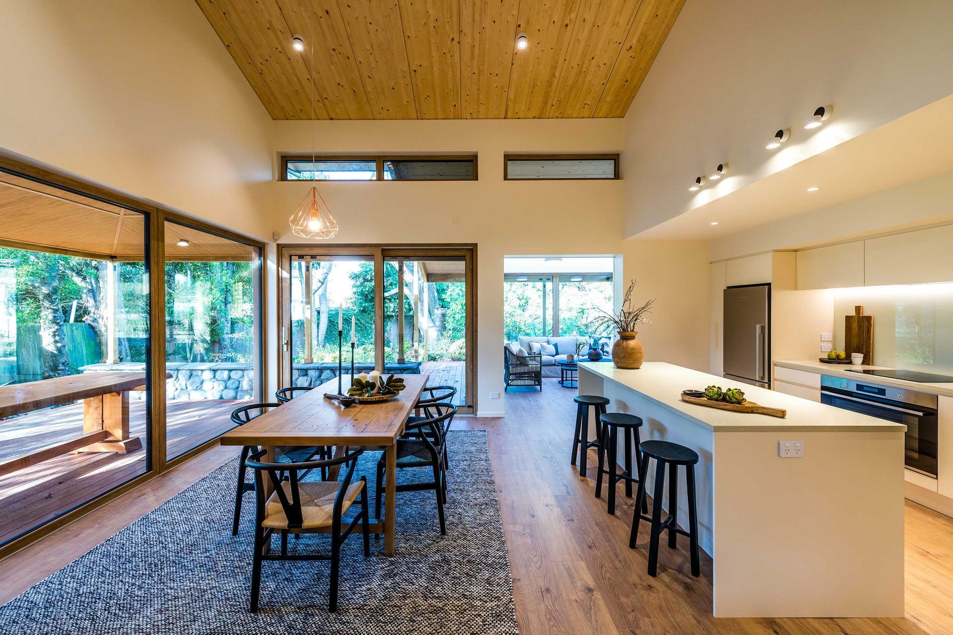 Kitchen dining looking towards sunroom. The ceiling is structural solid timber panels that have a warm roof on top.