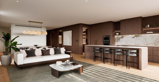 Open-plan contemporary interior combining a living room and kitchen. A white sofa with dark cushions faces a low coffee table, while the kitchen features extensive dark timber cabinetry, a large island with seating, integrated appliances, open shelving, and a prominent veined stone splashback. Warm concealed lighting, neutral finishes, and a sculptural pendant create a refined, inviting atmosphere.