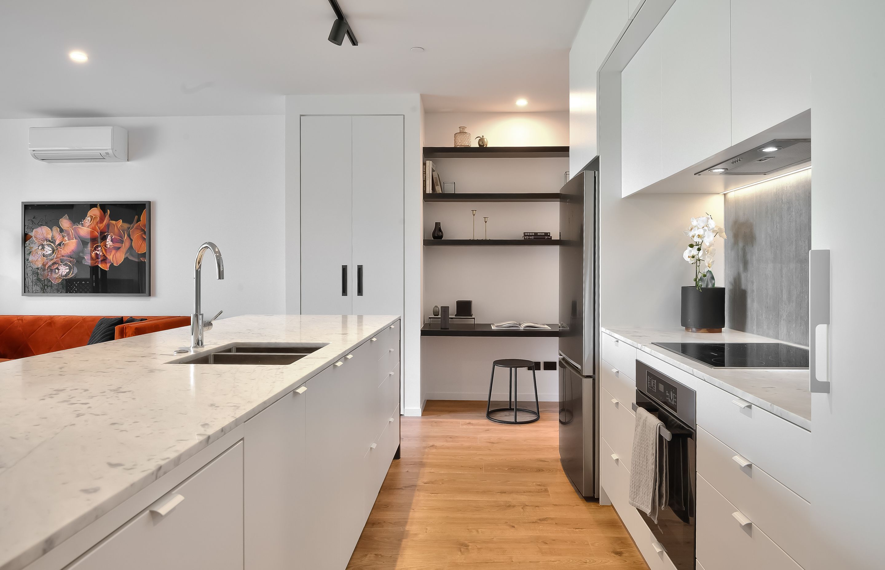 The interiors are sleek and edgy,  juxtaposing glossy and textured materials. Timber floors, concrete-look tiles and matte kitchen cabinetry complete the look.