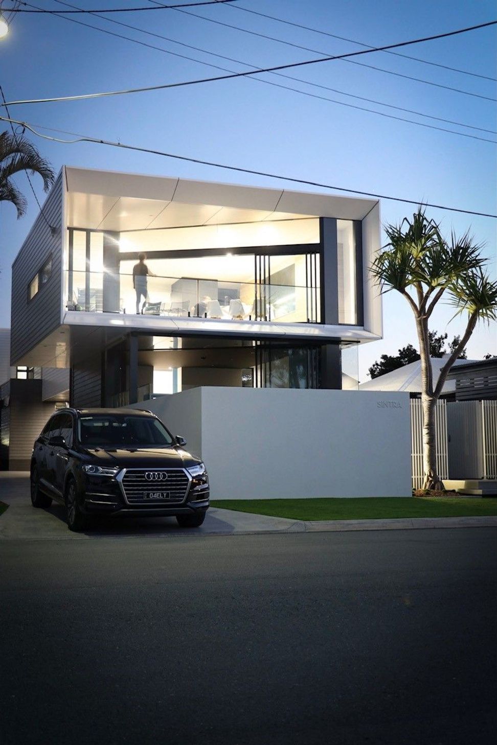 Kruger Residence - Exterior. Upper level balcony and rendered base with garden planting.