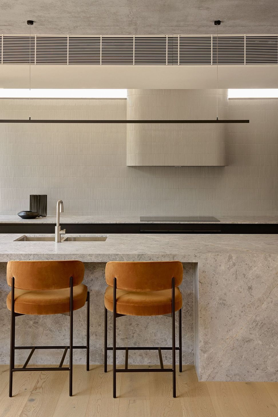 Wildflower Residence - Kitchen. Stone island with leather stools and a concealed rangehood.