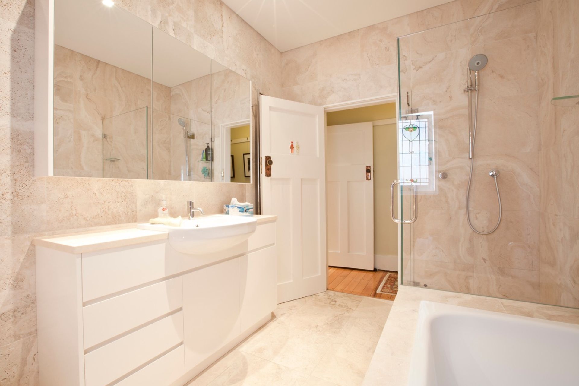 Fully tiled travertine bathroom with custom designed joinery