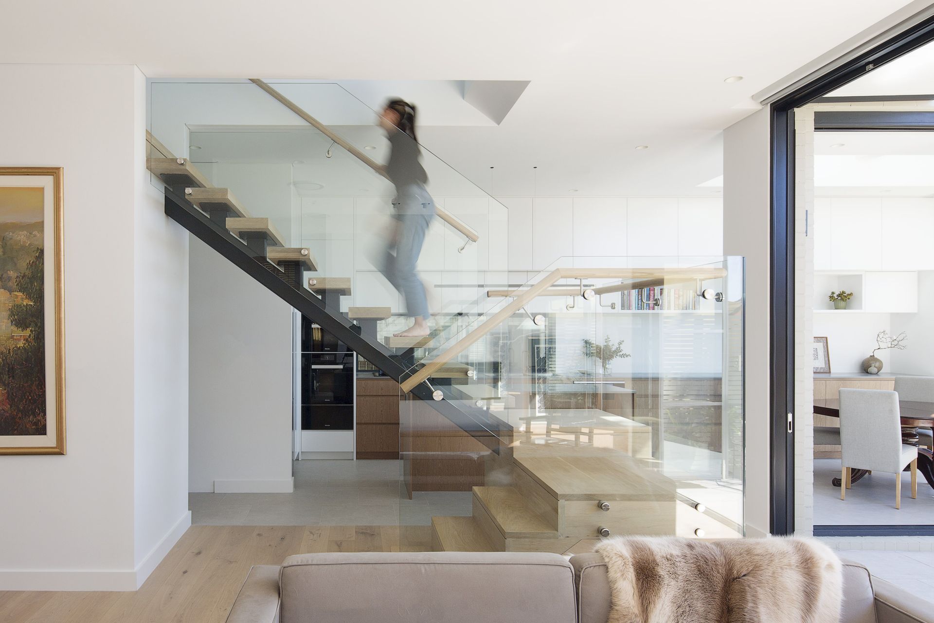 A central staircase as a threshold between the kitchen and living space. A void over provides light through all spaces.