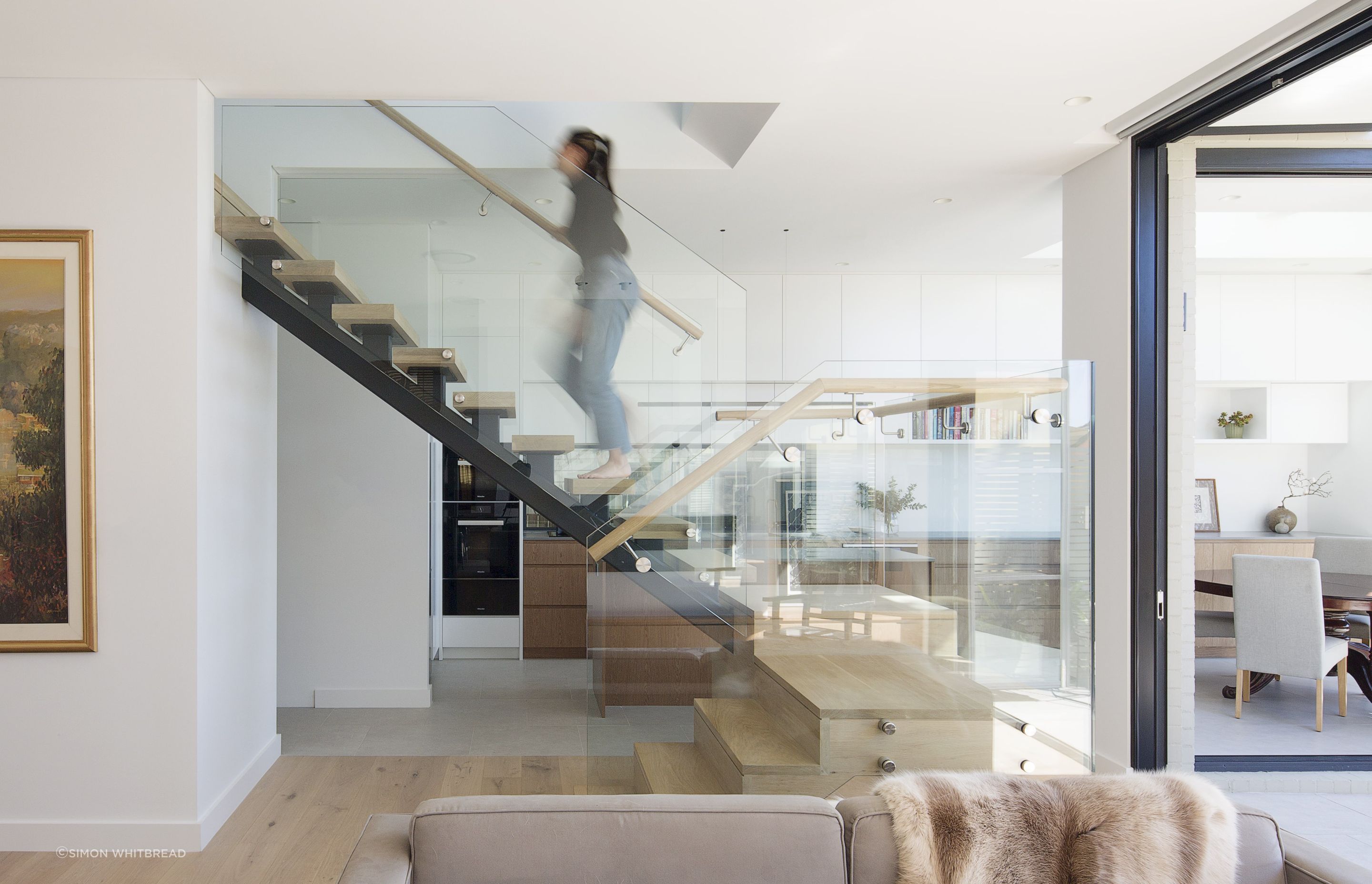 A central staircase as a threshold between the kitchen and living space. A void over provides light through all spaces.