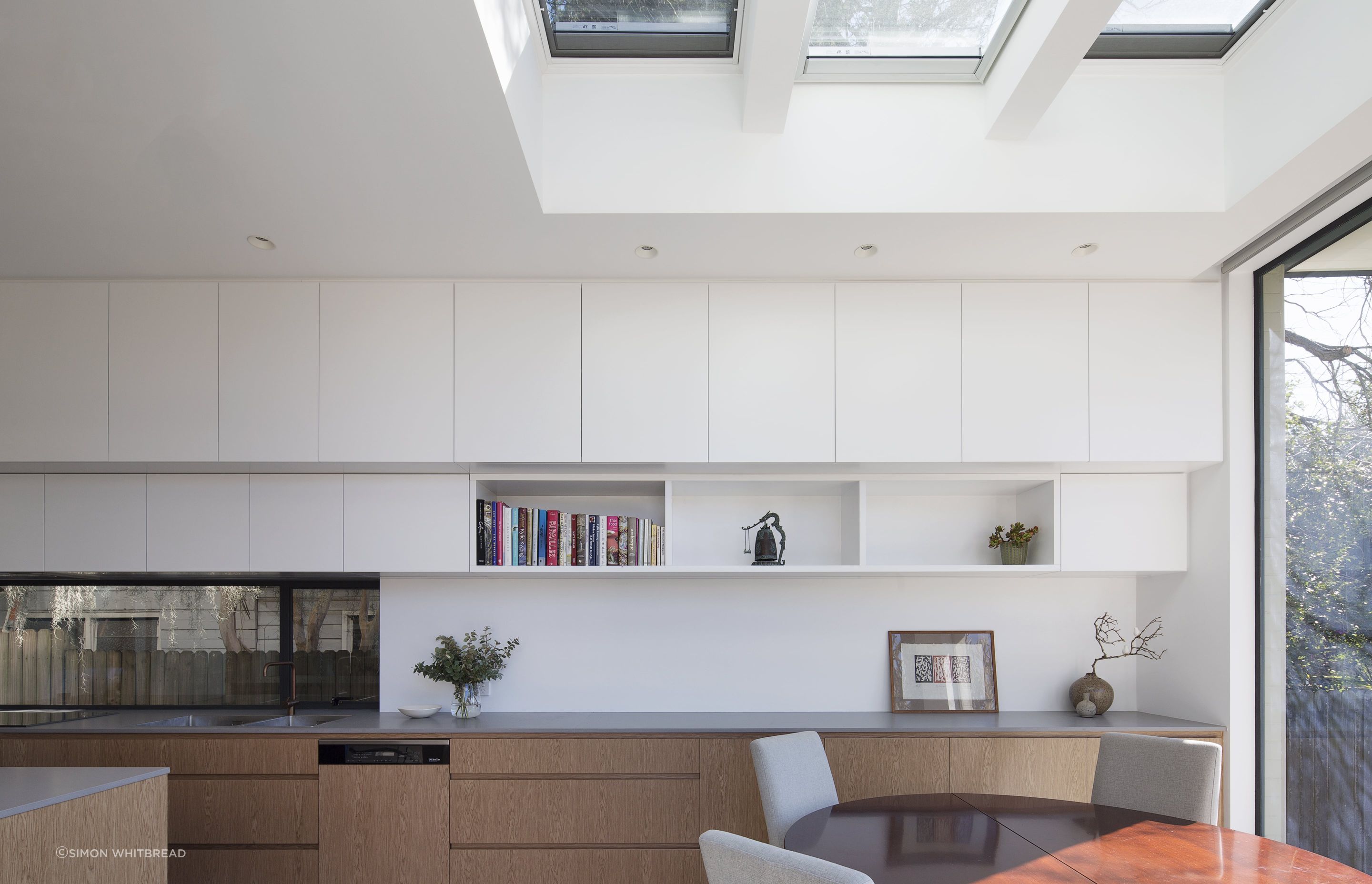A simplistic kitchen layered with textured materials. A window splashback allowed for natural light to reflect into the space.