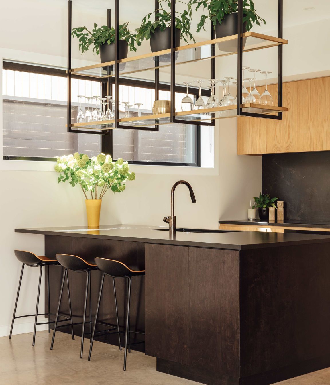 Suspended shelving above the island helps create a bar-like atmosphere around the kitchen.
