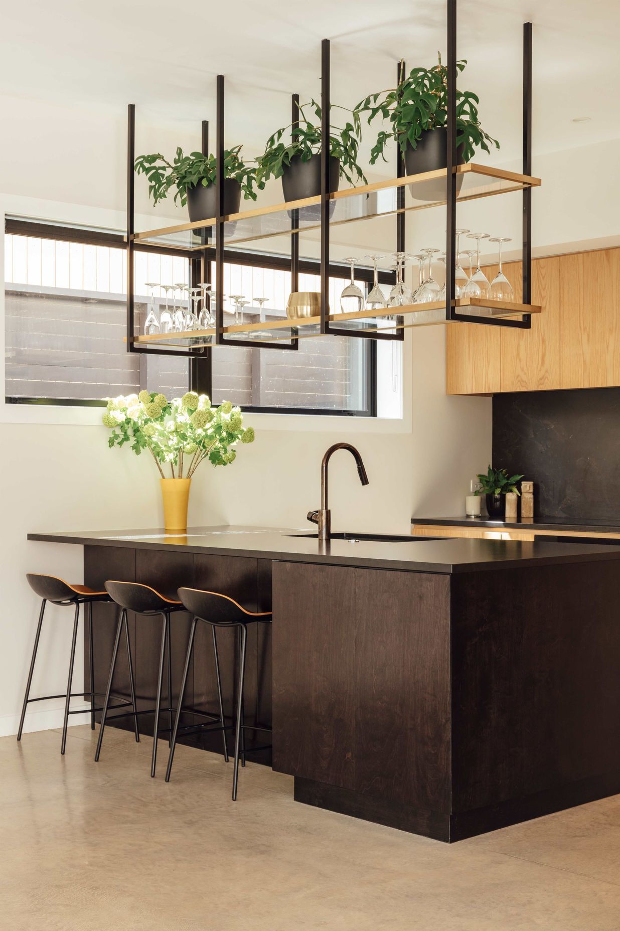 Suspended shelving above the island helps create a bar-like atmosphere around the kitchen.