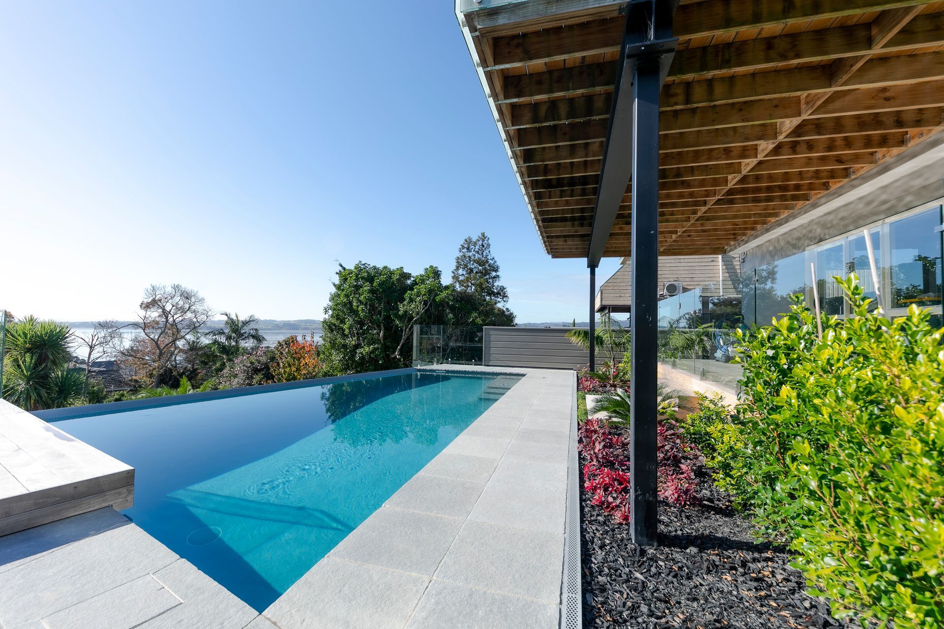 A huge transformation took place in this backyard - designed by Guy Brackebush.  Hydrazzo Hatteras Gray Pool Plaster captures the peep of the view out to Shelley Park Beach.