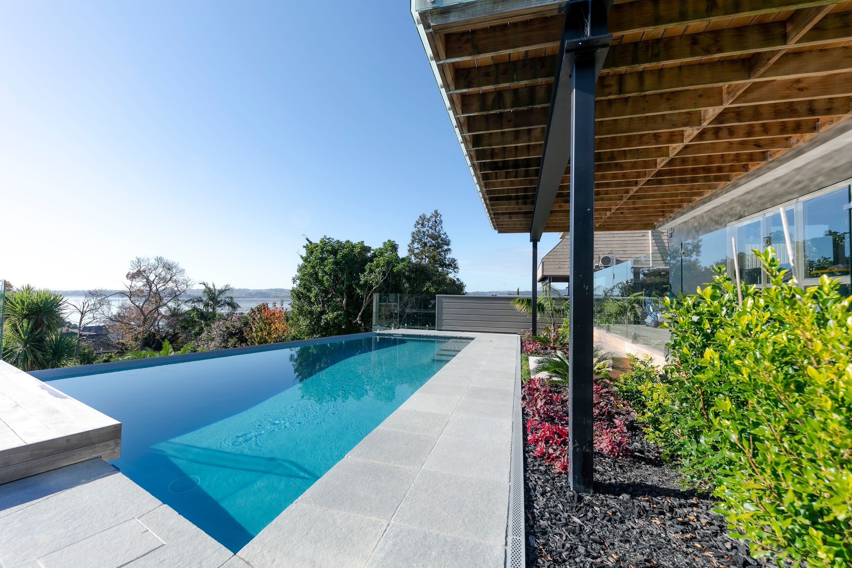 A huge transformation took place in this backyard - designed by Guy Brackebush. Hydrazzo Hatteras Gray Pool Plaster captures the peep of the view out to Shelley Park Beach.