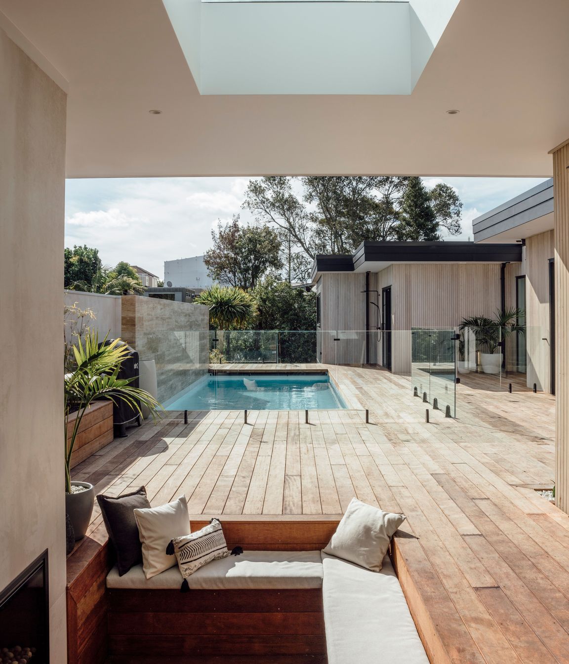 Tucked into the corner, a conversation pit with open fire provides a more intimate space within the wider outdoor entertaining area.