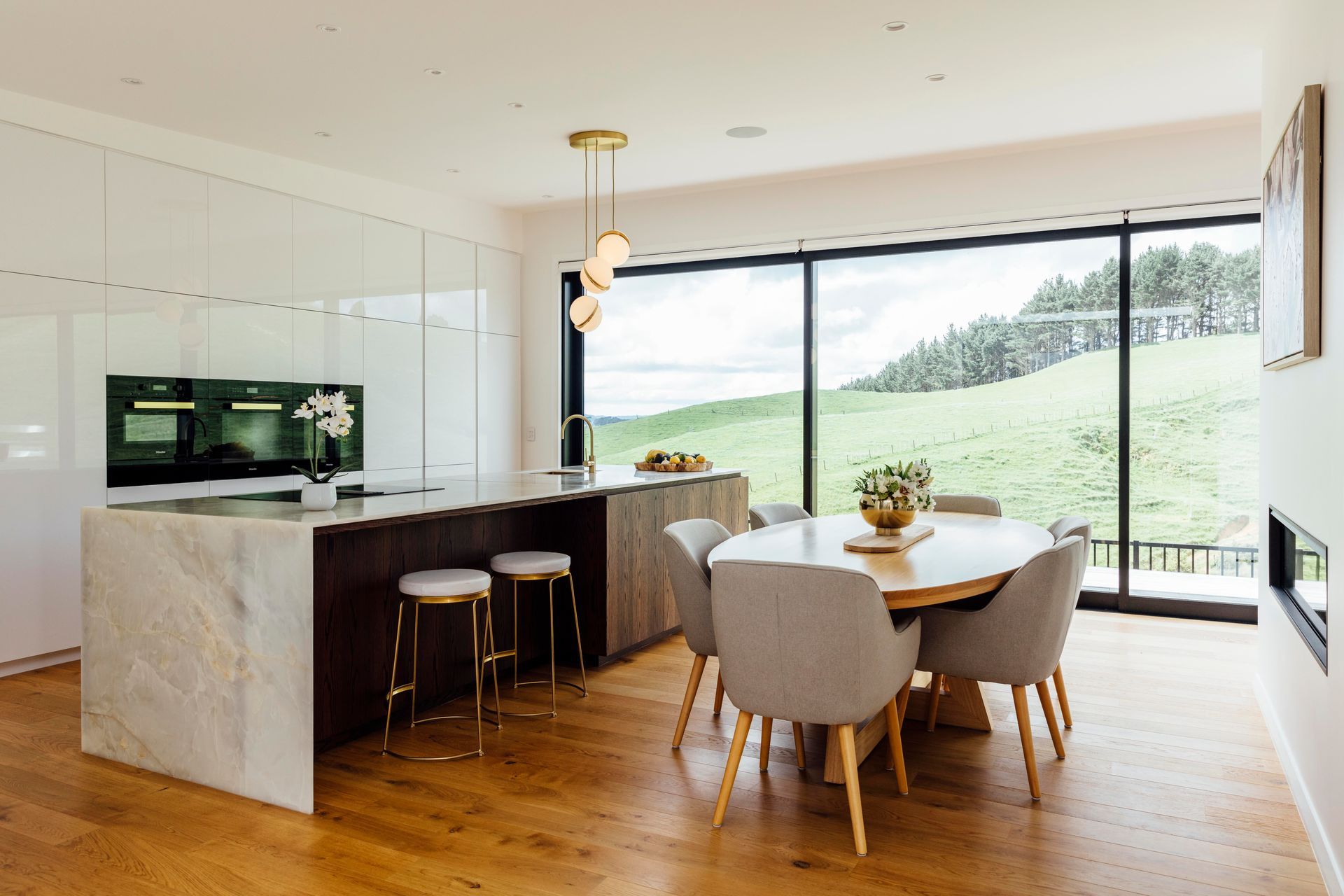 The kitchen, designed by Leonie Hamill from Cube Dentro, has glossy white cabinetry, a benchtop of white Iranian onyx and a Phoenix Vivid Slimline sink mixer. A Lee Broom mini crescent chandelier is the final touch.