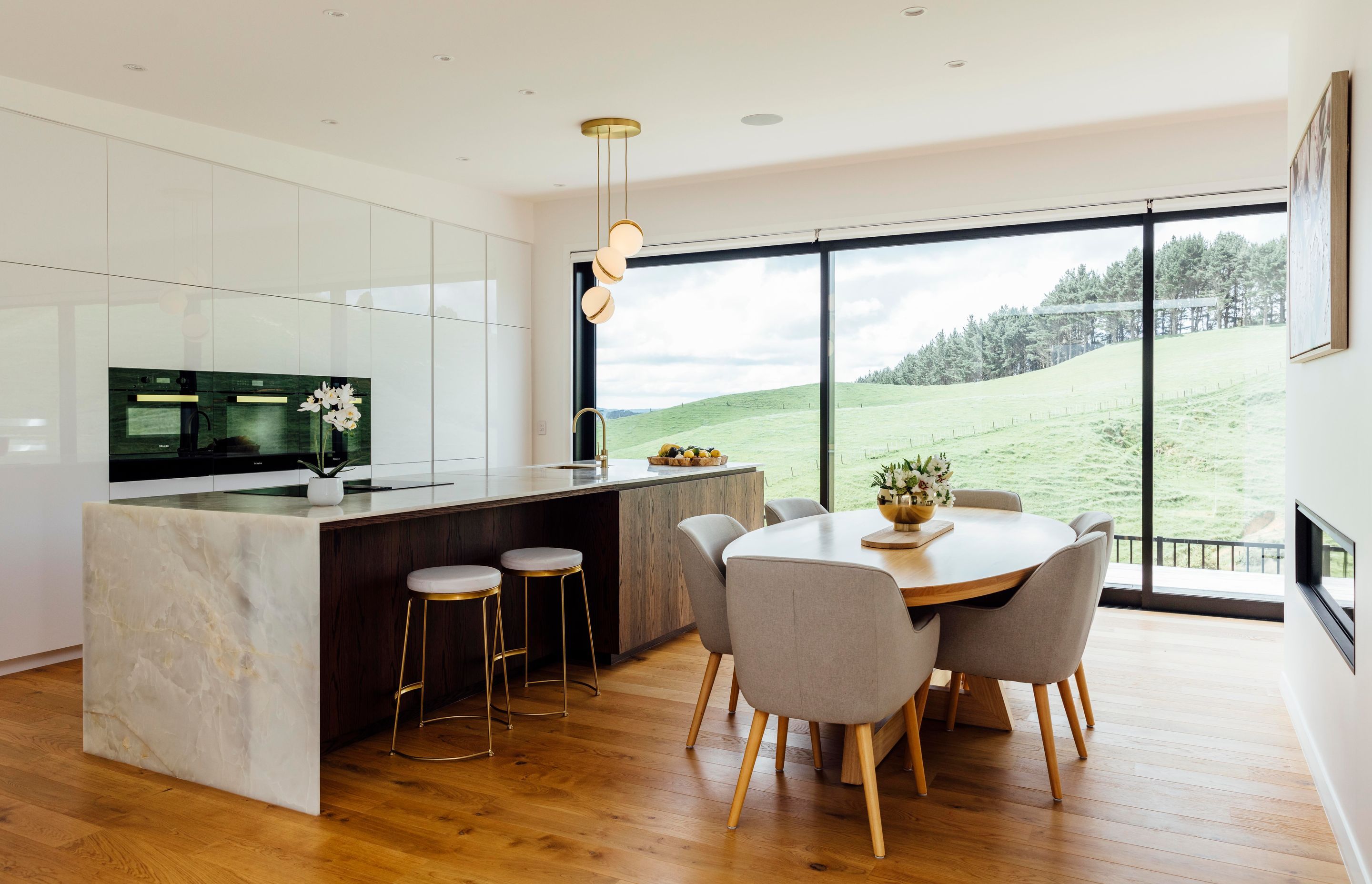 The kitchen, designed by Leonie Hamill from Cube Dentro, has glossy white cabinetry, a benchtop of white Iranian onyx and a Phoenix Vivid Slimline sink mixer. A Lee Broom mini crescent chandelier is the final touch.