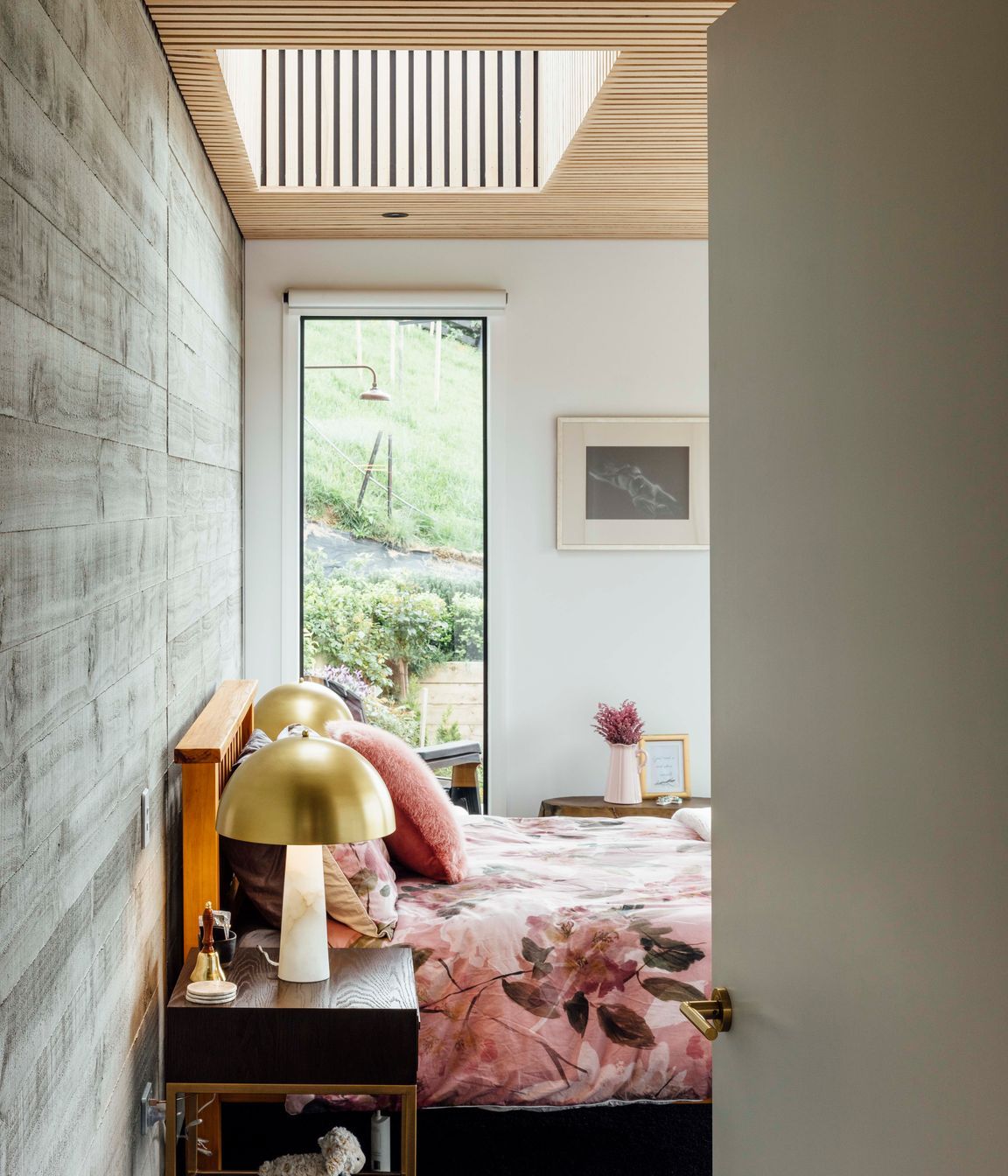 A roughsawn, timber-finished concrete wall in the main bedroom and ceilings clad in American ash battens bring texture to the material palette.
