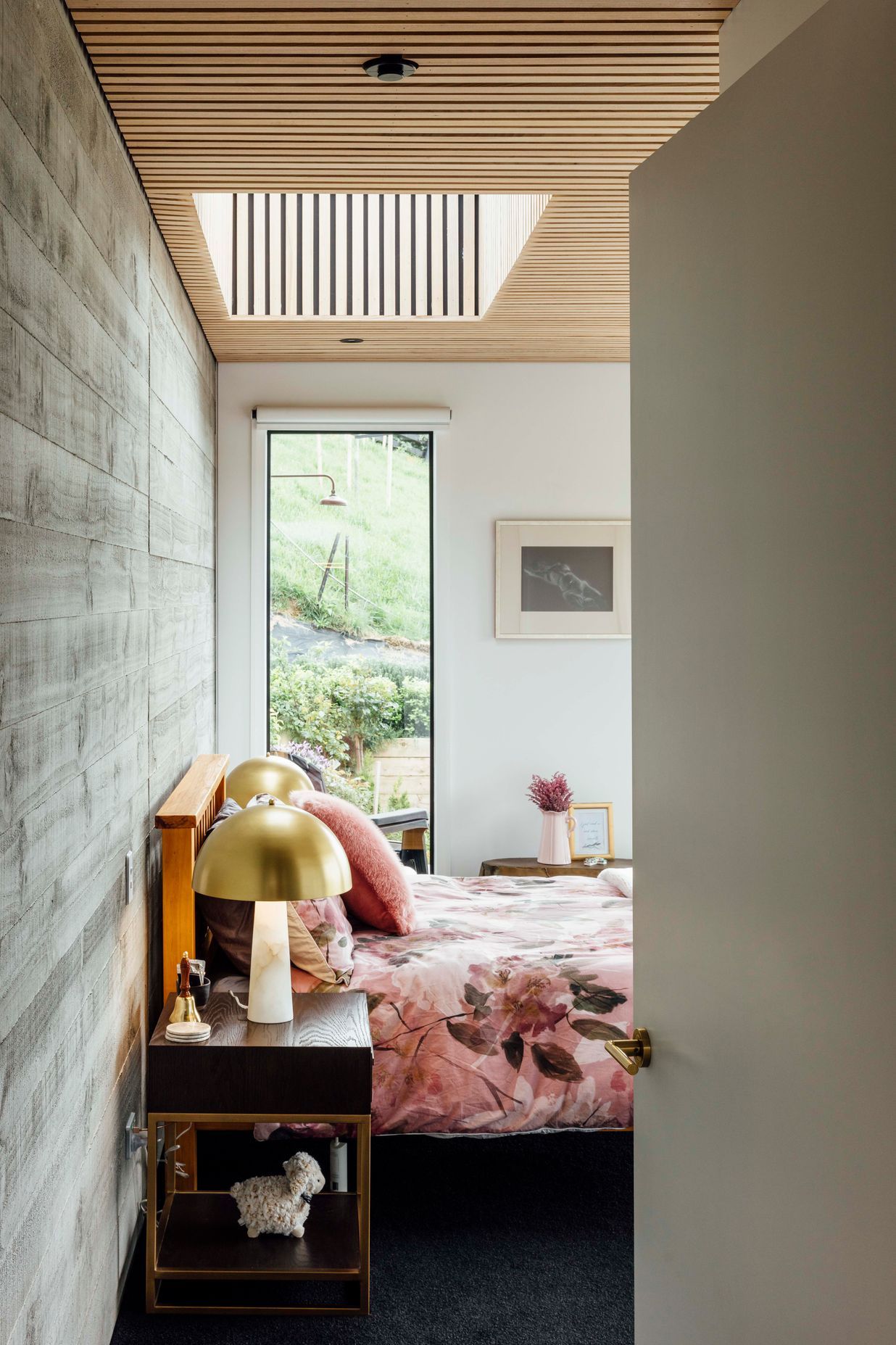 A roughsawn, timber-finished concrete wall in the main bedroom and ceilings clad in American ash battens bring texture to the material palette.