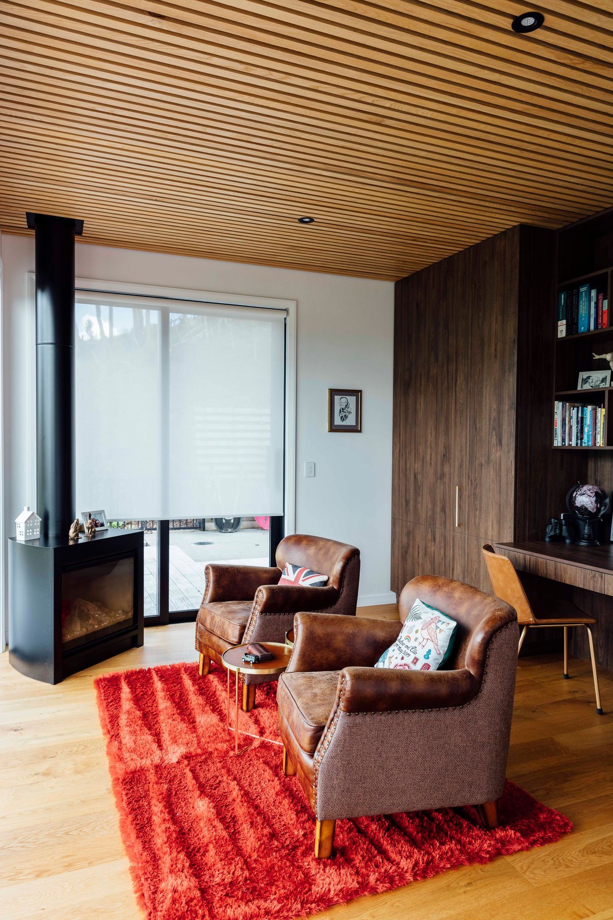 Vintage chairs within the reading room accompanied by a cozy fireplace and contrasting ceilings.