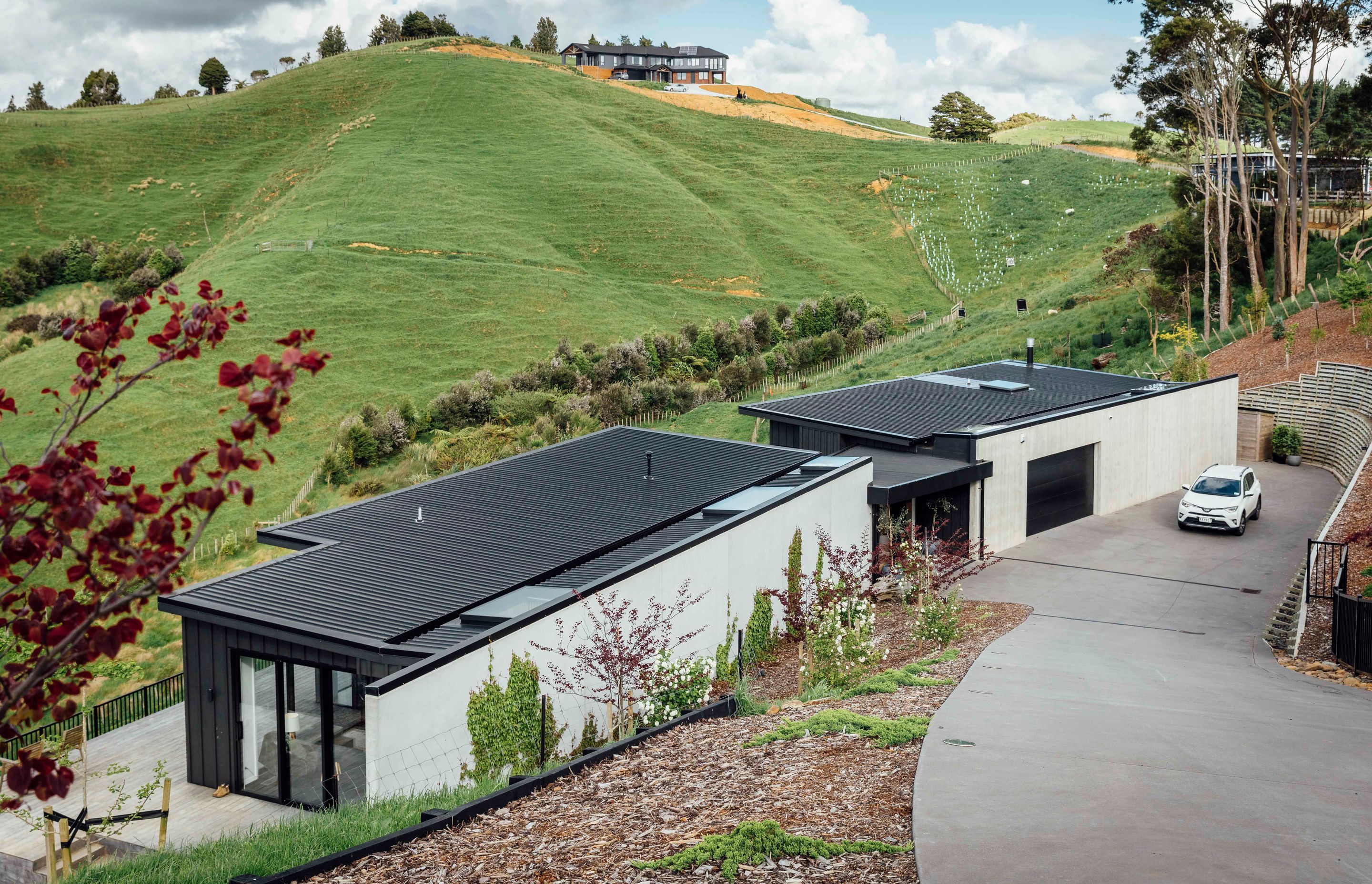Robust materials including Colorsteel longrun roofing in 'Ebony' and a spine of concrete tilt panels anchor the dwelling to the hillside. The owners have planted Boston ivy to clamber over and soften the concrete wall.