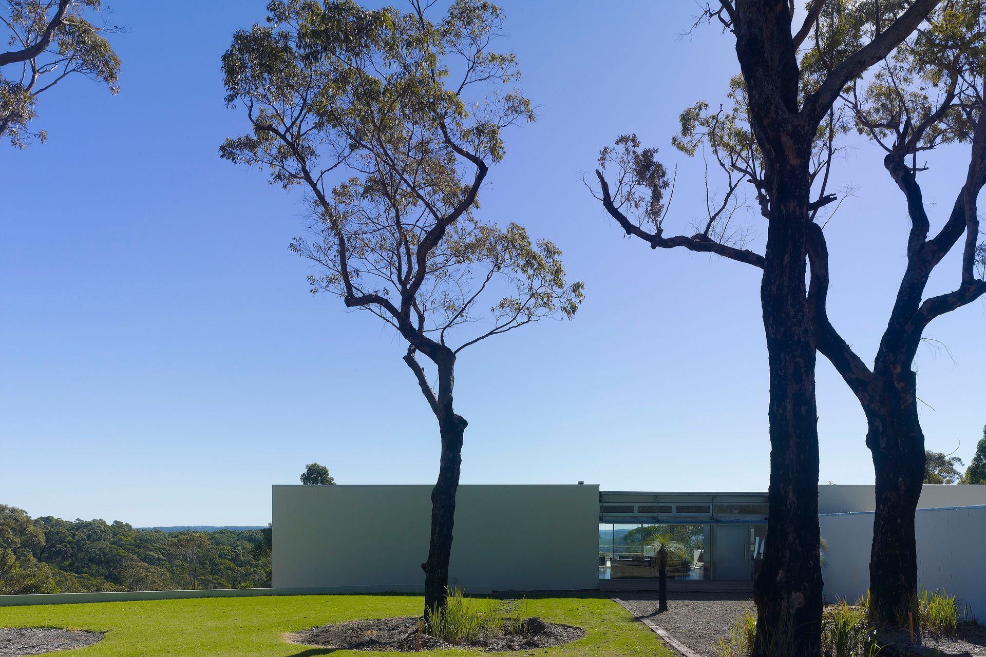 The dwelling frames a lawn forecourt.