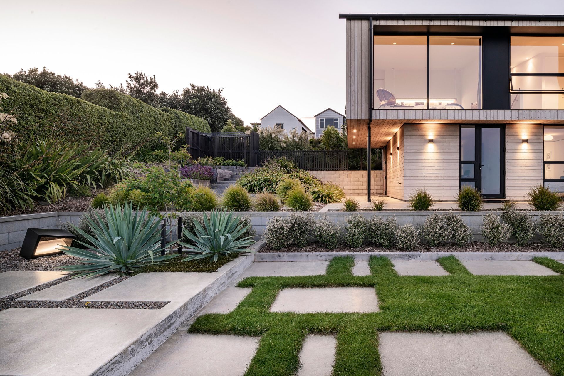 A paved seating area adjacent to the lawn terrace. Terraced vegetable garden and screened service area are above.