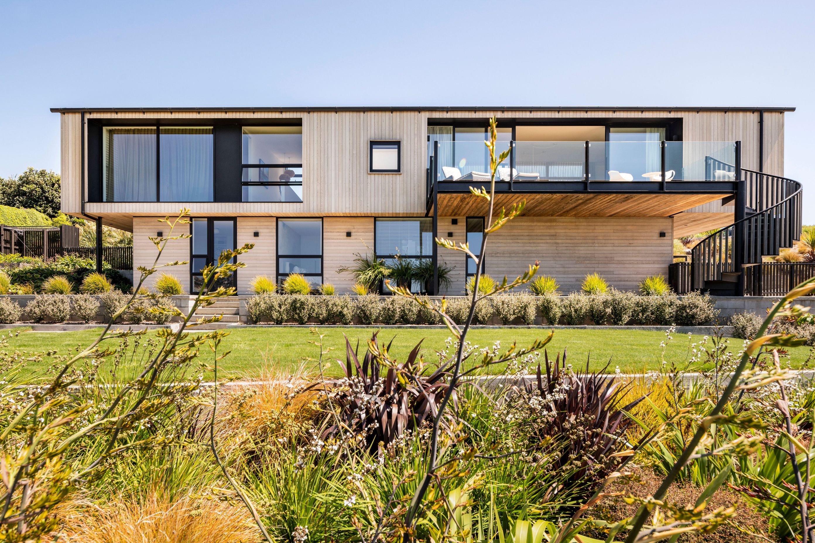 Swathes of native planting wrap around the lower lawn terrace