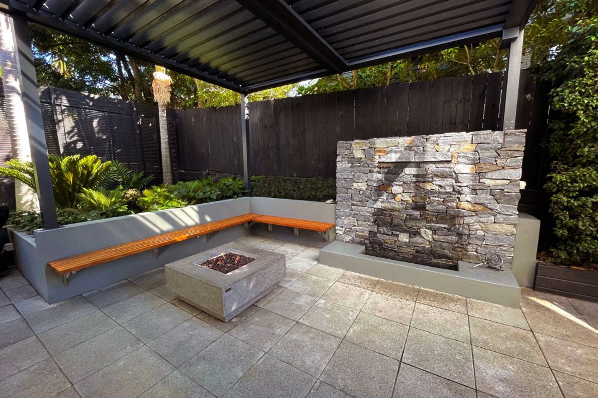 Patio with Locarno Louvered pergola, fire pit and water feature