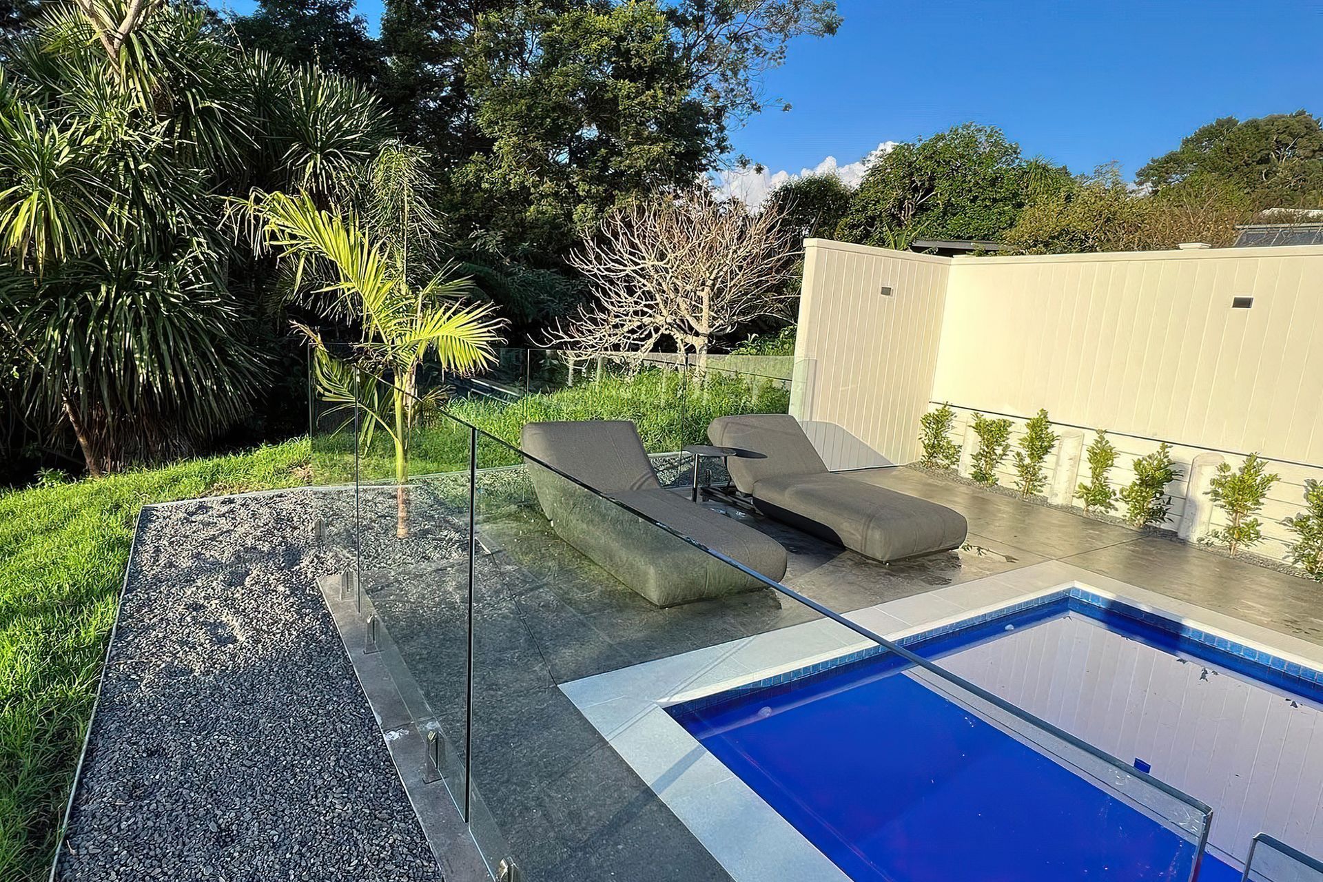Comfortable grey pool chairs sat in front of a deep blue pool