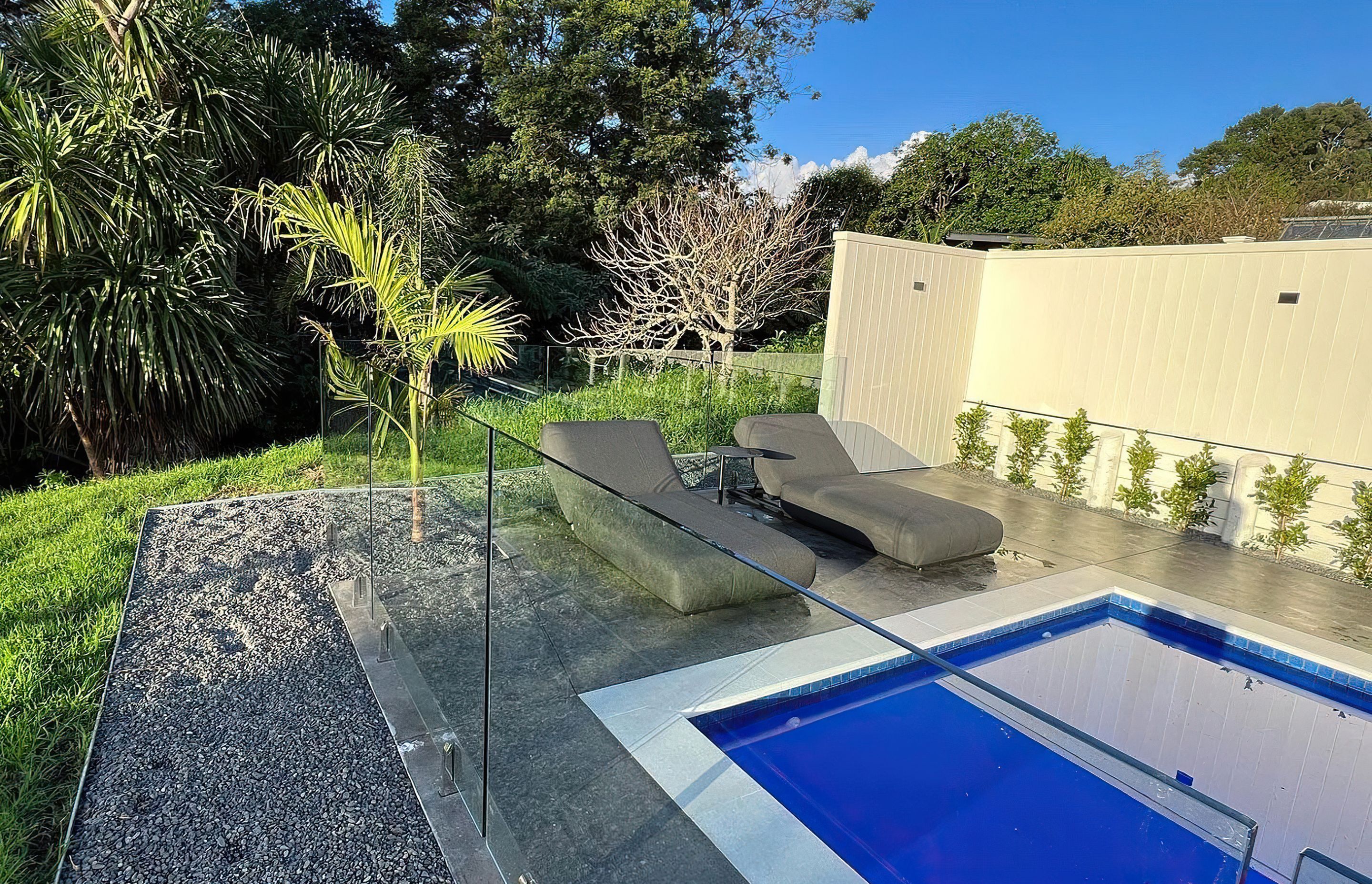 Comfortable grey pool chairs sat in front of a deep blue pool