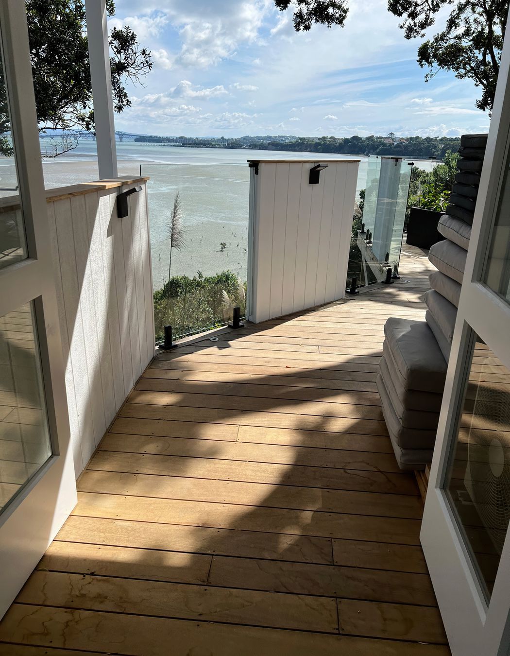 Wooden deck with a mixture of white painted wood and glass barriers overlooking the sea